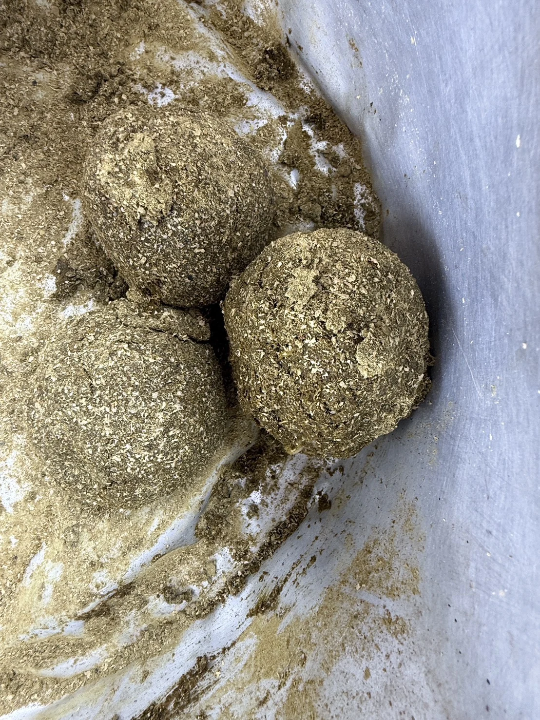 Three prepared supplement balls held above a bowl at Somboon